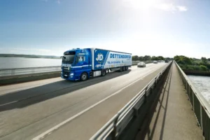 blauer Lkw der Dettendorfer Spedition fährt über eine Brücke