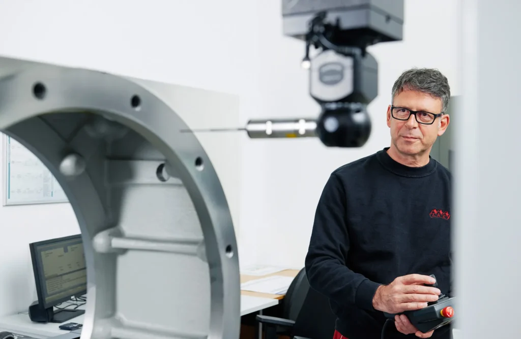 Mitarbeiter der ZAE Antriebssysteme an seinem Arbeitsplatz in der Qualitätskontrolle fotografiert von Benno Cray Businessfotograf.